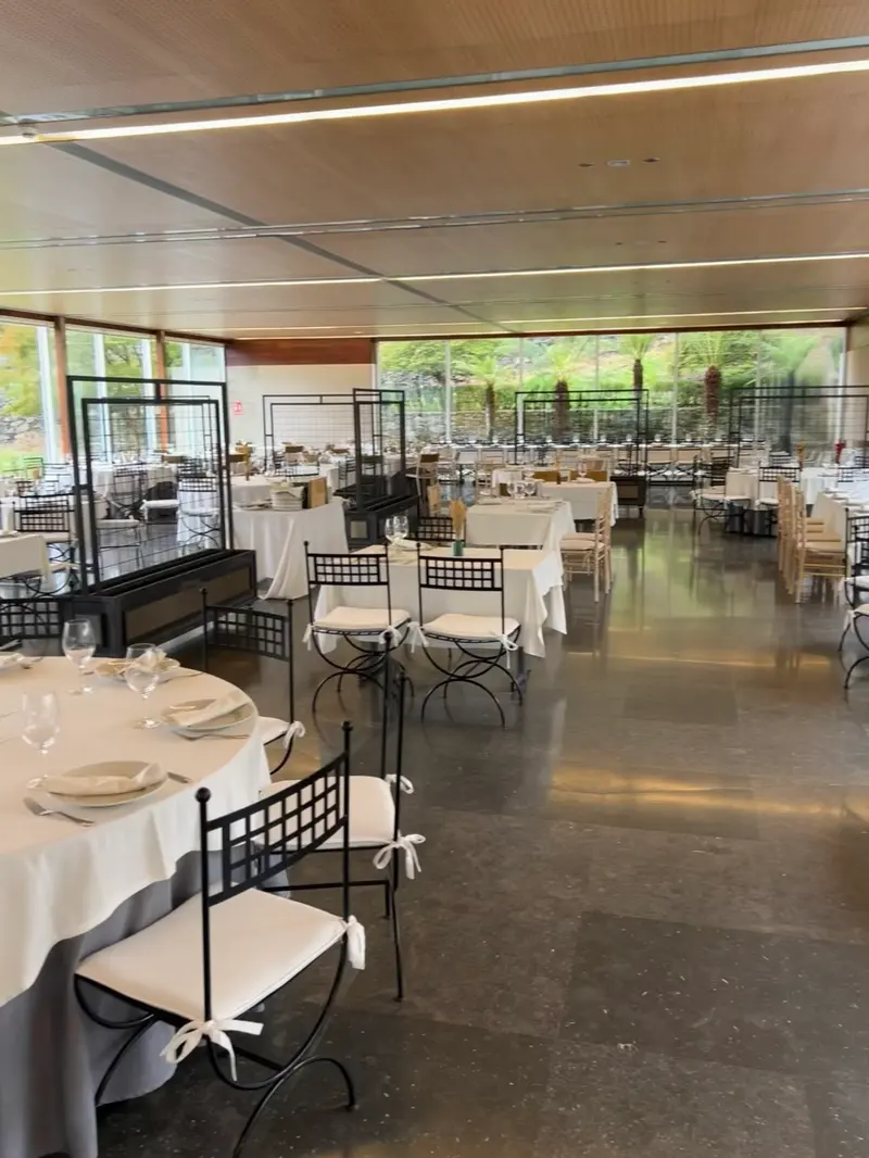 Comedor acristalado montado, con sillas negras de hierro y manteles blancos