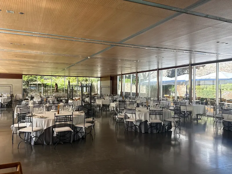 Pabellón acristalado montado para un banquete, con mesas redondas y vistas al jardín